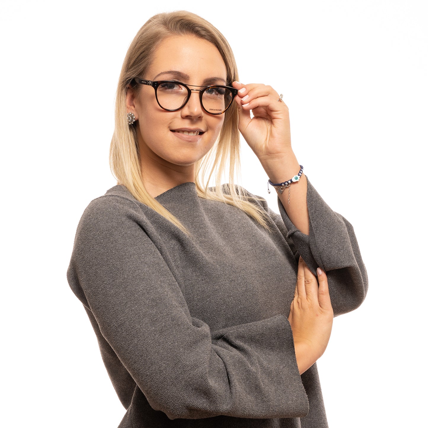 Woman wearing glasses and gray sweater, posing confidently against a white background.