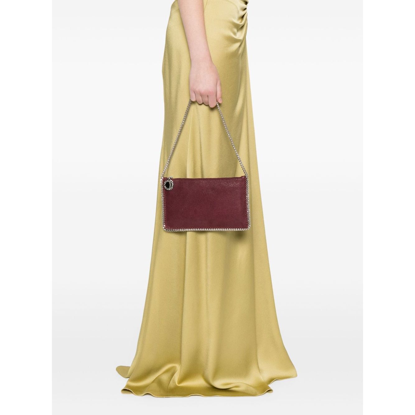 Model holding Stella McCartney Falabella clutch in amaranth purple with chain-link shoulder strap.