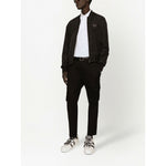 Model wearing Dolce & Gabbana Logo cotton polo shirt with black jacket and pants, showcasing logo plaque and short sleeves.
