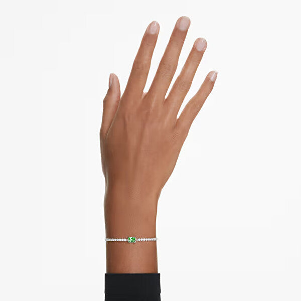 Elegant hand wearing a Swarovski bracelet with a green gemstone centerpiece