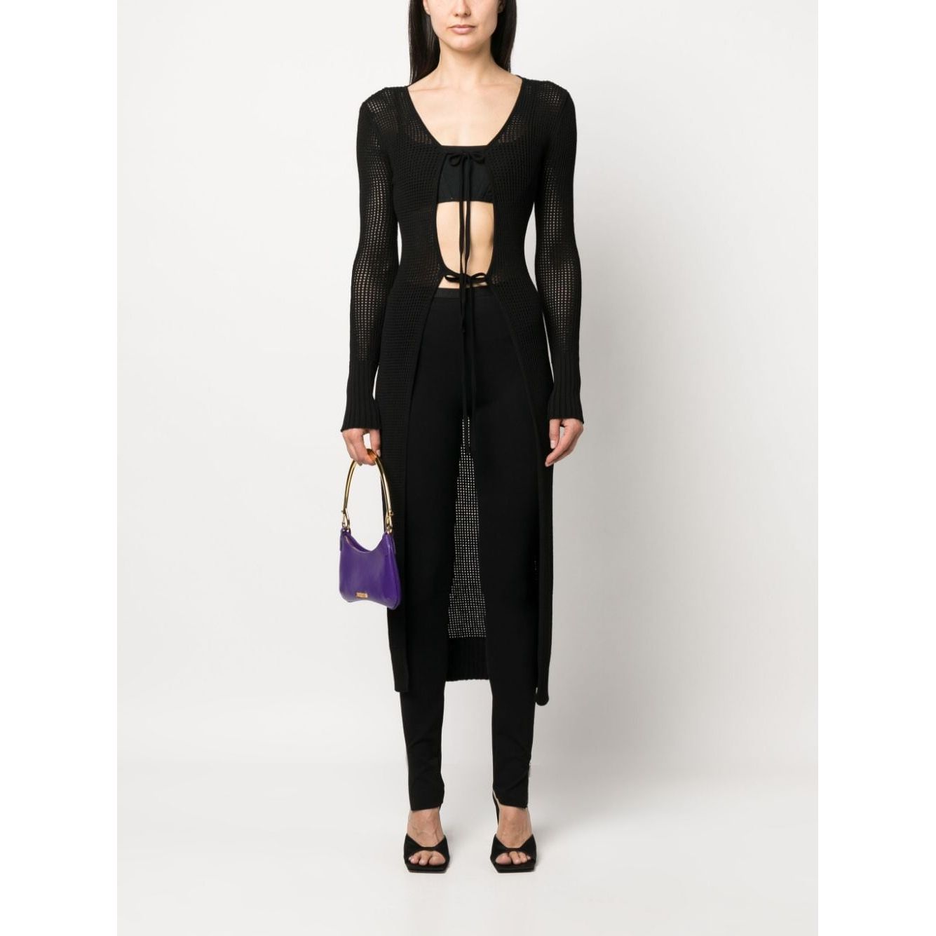 Model wearing ANDREĀDAMO Andrea Adamo Sweaters Black, semi-sheer knitted cardigan with racerback, long sleeves, and front tie fastening.