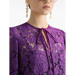Close-up of Dolce & Gabbana bell sleeves Lace mini dress in amethyst purple with front tie and crew neck details.