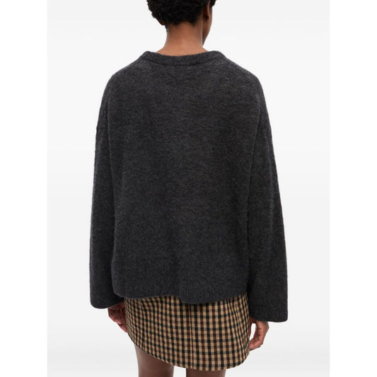 GANNI Sweaters Grey crew neck wool sweater with long sleeves, ribbed cuffs, and straight hem, shown from the back on a model in plaid skirt.