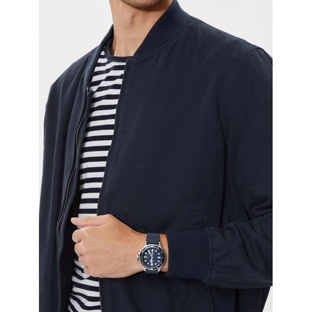 Man wearing NAUTICA Mod. NAPCBS304 quartz analog watch with bracelet, 43mm case, and 5 ATM water resistance, styled with navy jacket and striped shirt.