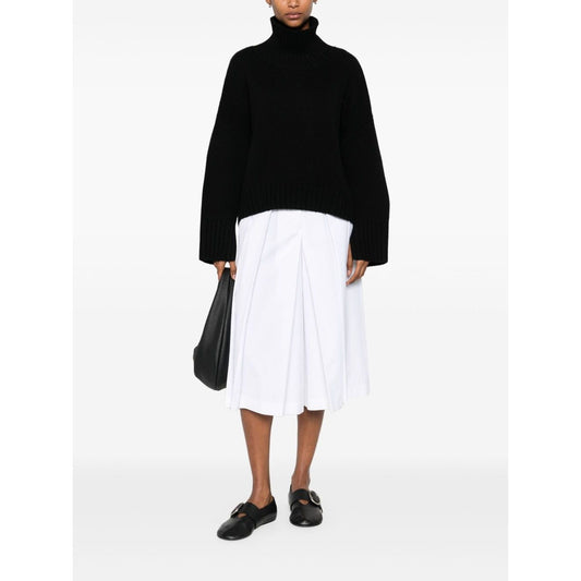Woman wearing SOFT GOAT Sweaters Black cashmere turtle-neck jumper with ribbed trim and high neck, styled with a white skirt and black shoes.