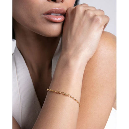 Elegant lady wearing a thin gold bracelet on her wrist, shown against a neutral background, showcasing delicate fashion jewelry style.
