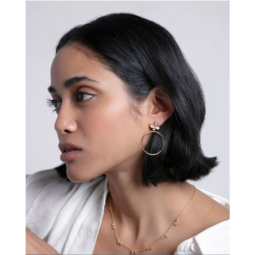 Woman wearing elegant gold hoop earrings and a delicate necklace, showcasing minimalist jewelry fashion.