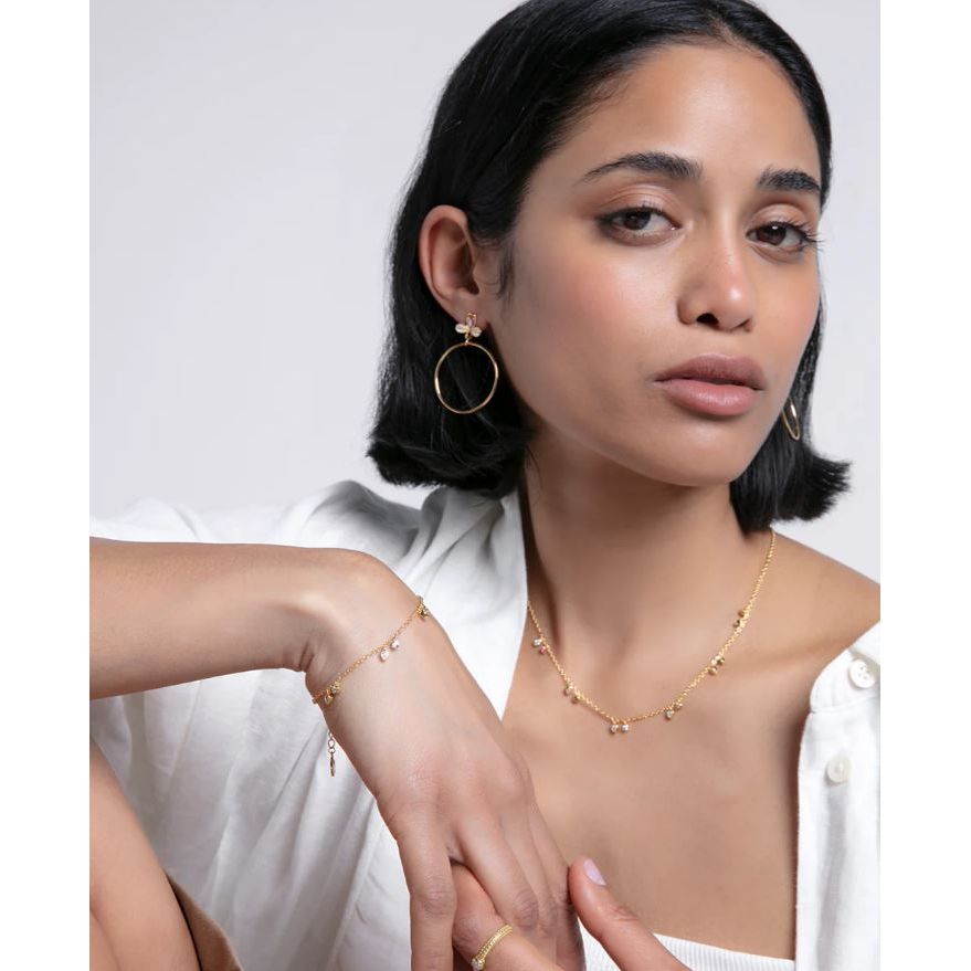 Woman wearing gold jewelry including earrings and a bracelet, showcasing a stylish look.