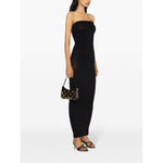 Woman wearing Wolford Dresses Black, strapless ribbed knit tube dress with an elasticated hem, paired with a small black handbag and heels.