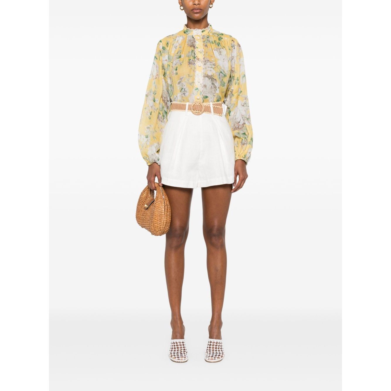 Model wearing Zimmermann Shorts Ivory with a high-waisted design, belt loops, and side slit pockets, paired with a floral blouse.